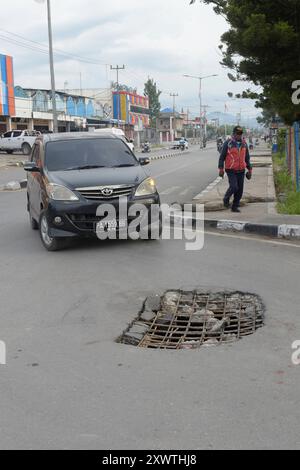 Wer in Wamena von der Hauptstraße in diese Seitenstraße abbiegt, muss aufpassen, keinen Unfall zu bauen. Unter dem Asphalt verläuft ein Abwasserkanal und die Teerdecke ist an einer stelle durchbrochen. DAS gleiche gilt für den Gehweg, wo einzelne Betonplatten verschoben sind. *** Chiunque chiuda la strada principale in questa strada laterale a Wamena deve fare attenzione a non causare incidenti Una fogna corre sotto l'asfalto e la superficie del catrame è rotta in un posto lo stesso vale per il marciapiede, dove le singole lastre di cemento si sono spostate Foto Stock