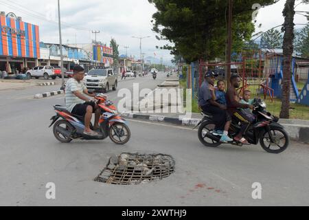 Wer in Wamena von der Hauptstraße in diese Seitenstraße abbiegt, muss aufpassen, keinen Unfall zu bauen. Unter dem Asphalt verläuft ein Abwasserkanal und die Teerdecke ist an einer stelle durchbrochen. DAS gleiche gilt für den Gehweg, wo einzelne Betonplatten verschoben sind. *** Chiunque chiuda la strada principale in questa strada laterale a Wamena deve fare attenzione a non causare incidenti Una fogna corre sotto l'asfalto e la superficie del catrame è rotta in un posto lo stesso vale per il marciapiede, dove le singole lastre di cemento si sono spostate Foto Stock