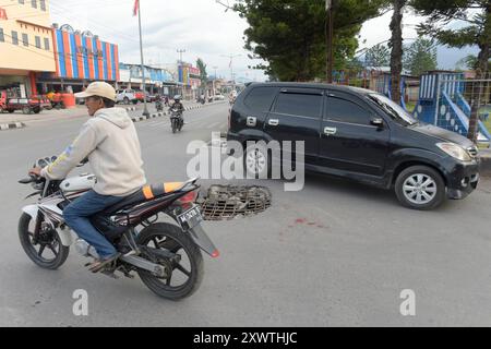 Wer in Wamena von der Hauptstraße in diese Seitenstraße abbiegt, muss aufpassen, keinen Unfall zu bauen. Unter dem Asphalt verläuft ein Abwasserkanal und die Teerdecke ist an einer stelle durchbrochen. *** Chiunque chiuda la strada principale in questa strada laterale a Wamena deve fare attenzione a non causare un incidente Una fogna corre sotto l'asfalto e la superficie del catrame è rotta in un posto Foto Stock