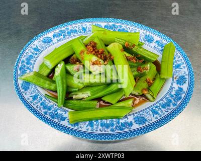 A fette di vapore Ladies Fingers o okra con cipolle fritte in profondità per preparare un delizioso piatto di verdure locali a Penang Malesia Foto Stock