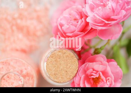 sale aromatico. Set di sali da bagno spa in vasetti di vetro e fiori di rose su sfondo bianco shabby. Sale rosa con estratto di rosa e fragranza Foto Stock