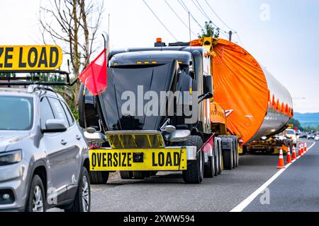 Semi-carro industriale nero rotto con cofano aperto e turbina di carico sovradimensionata su un carrello aggiuntivo fuori servizio sulla strada Foto Stock