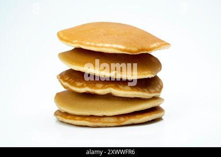 Una pila di pancake su sfondo bianco. I pancake sono dorati e sembrano essere appena fatti. Concetto di calore e comfort, come i pancake Foto Stock