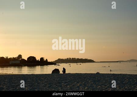 Mentre il sole tramonta sulla spiaggia di Ladeira, i visitatori sfruttano al meglio i raggi d'oro finali della giornata. Il caldo bagliore del sole della sera proietta lunghe ombre sul Foto Stock