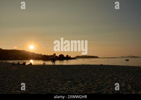 Mentre il sole tramonta sulla spiaggia di Ladeira, i visitatori sfruttano al meglio i raggi d'oro finali della giornata. Il caldo bagliore del sole della sera proietta lunghe ombre sul Foto Stock