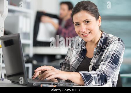 una donna felice che utilizza un notebook per analizzare il server Foto Stock