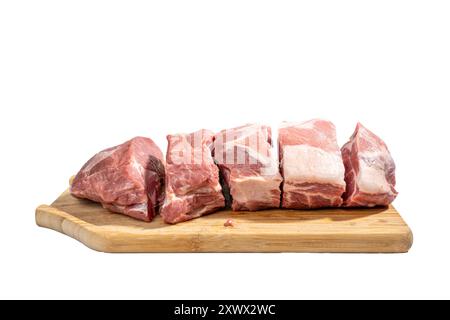 Una lastra di carne viene tagliata a pezzi e disposta su un tagliere di legno. La carne è cruda e cruda, ed è una varietà di tagli diversi. Concetto Foto Stock