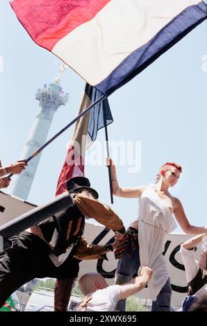 Gruppo di persone che celebrano con entusiasmo la Festa della Bastiglia a Parigi, innalzando la bandiera francese sullo sfondo della colonna di luglio. Una forte metafora della libertà, dell'unità e dell'orgoglio nazionale. Parigi, 14 anni. Juli 2003 Foto Stock