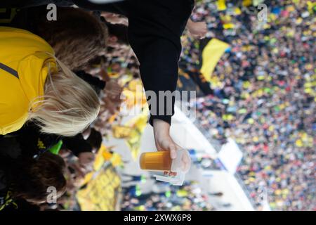 Una foto vibrante dei fan del Borussia Dortmund al Niedersachsenstadion di Hannover, 2011. L'immagine presenta una folla energica, con un'attenzione particolare a una tazza di birra di plastica, che simboleggia l'entusiasmo e lo spirito dei fandom del calcio. Foto Stock