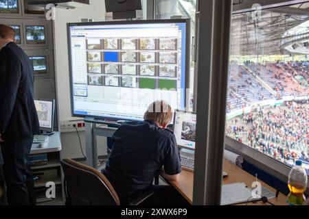 Il personale di sicurezza supervisiona la gestione della folla nella sala di controllo del Niedersachsenstadion di Hannover. La tecnologia di sorveglianza aiuta a monitorare i tifosi durante una partita del 2011, garantendo sicurezza e ordine. L'immagine cattura l'essenza di operazioni di sicurezza efficaci negli eventi sportivi. Foto Stock