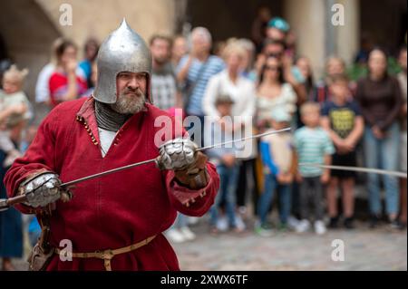 Jaunpils, Lettonia - 10 agosto 2024: I partecipanti si impegnano in una rievocazione indossando un'armatura medievale storica. Foto Stock