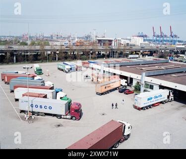 Una vivace stazione di sdoganamento dei container ad Altenwerder, Amburgo. In una giornata limpida si vedono diversi camion e container, simboleggiando l'efficienza del commercio globale e della logistica. Foto Stock