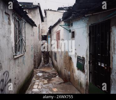 Immagine di uno stretto vicolo nel Barrio 6 de Maio, Lisbona, con edifici in rovina realizzati con materiali economici. L'area mostra segni di abbandono con graffiti e rifiuti visibili ovunque. 2006 Foto Stock