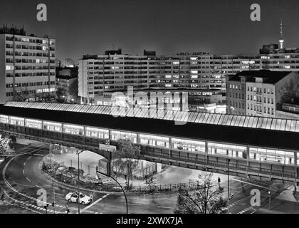 L'immagine in bianco e nero di Kottbusser Tor a Kreuzberg di Berlino mostra l'architettura urbana e la vivace vita notturna della città. La foto evoca sentimenti di connessione e solitudine, una metafora della dualità della vita moderna. Foto Stock