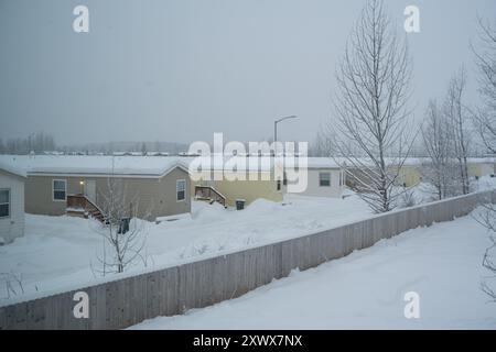 Una tranquilla scena invernale che mostra case mobili coperte di neve in un parcheggio per roulotte ad Anchorage, Alaska. L'immagine trasmette quiete e tranquillità in mezzo alle dure condizioni invernali. Foto Stock