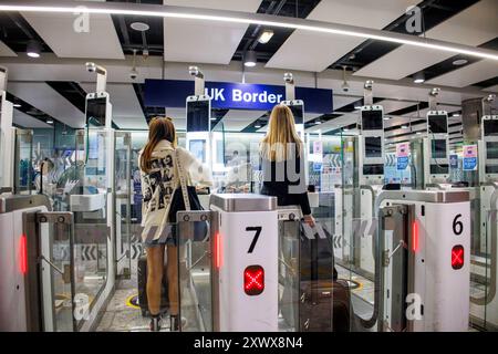 Passeggeri aerei in arrivo al gate del check-in al confine con il Regno Unito al Terminal 3 di Heathrow. Usano il riconoscimento facciale al cancello del check-in automatico. Foto Stock