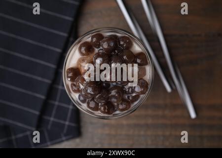 Gustoso tè a bolle di latte in bicchiere e cannucce su un tavolo di legno, piatto Foto Stock