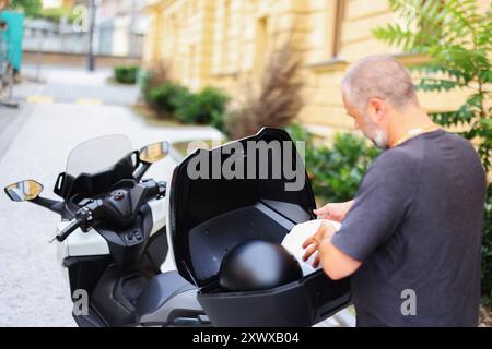 l'uomo mette i caschi nel bagagliaio di una motocicletta. concetto di guida sicura per le motociclette Foto Stock