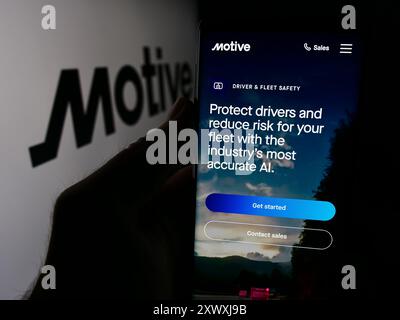 Persona che detiene lo smartphone con pagina Web della società di software per autotrasporti statunitense Motive Technologies Inc. Con logo. Messa a fuoco al centro del display del telefono. Foto Stock