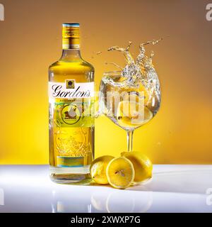 Bottiglia di Gin di limone siciliano Gordons, limoni e gin in vetro con spruzzi Foto Stock