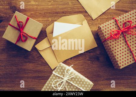 Inviti per la festa. Vista dall'alto ravvicinata delle confezioni regalo e delle buste aperte adagiate sulla grana rustica di legno Foto Stock