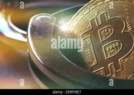 Vista macro di un bitcoin dorato sullo sfondo delle manette. Divieto di vendita e acquisto di bitcoin e criptovalute. Foto Stock
