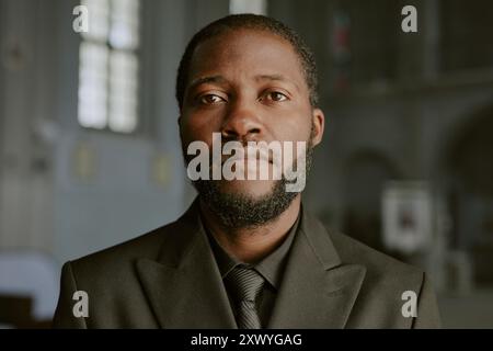 Ritratto di un uomo afroamericano vestito in costume nero, guarda la macchina fotografica con dolore negli occhi Foto Stock