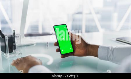 Persona anonima che utilizza uno smartphone con display Chromakey con schermo verde di occultamento con segnaposto Motion Tracker. Office Manager navigazione in Internet, acquisti online, scorrimento e tocco sul telefono Foto Stock