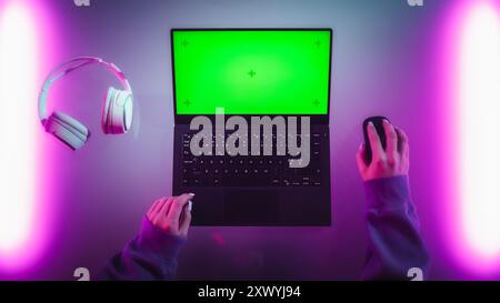 Foto dall'alto di una sviluppatrice software donna che lavora su un notebook in una stanza elegante con luci al neon. Computer con modello chiave Chroma Green Screen per servizi di marketing digitale, applicazioni, software Foto Stock