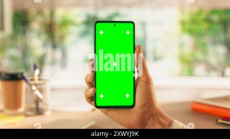 Vista POV di un Manager anonimo con smartphone con schermo verde. Vista in prima persona di un uomo che detiene un dispositivo con area isolata per app, software, promozione progettazione siti Web Foto Stock