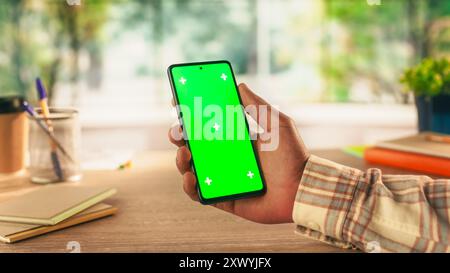 Persona nera anonima che utilizza uno smartphone con schermo Chromakey con occultamento verde e segnaposto Motion Tracker. Manager che naviga in linea nell'interfaccia utente di un'app, scorri e tocca il telefono Foto Stock