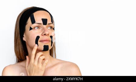La modella di bellezza della giovane donna applica nastri facciali neri sul suo viso. Foto Stock