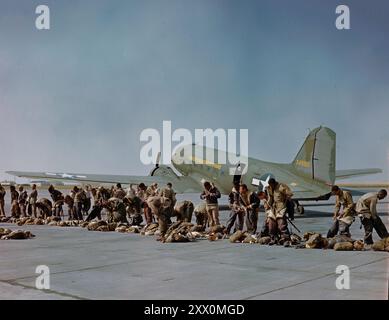 Operazione Firefly - i paracadutisti antincendio del 555th Parachute Infantry indossano le loro pesanti tute in pelle prima di salire a bordo di un C-47 del primo comando trasporto truppe. Presto si faranno strada verso un altro salto e un altro fuoco. Le loro attrezzature, tra cui due scivoli e di peso compreso tra 75 e 125 libbre, si trovano davanti a loro. Pendleton Army Air base, Pendleton, Oregon. CA. 1945 nell'aprile 1945 il 555th è stato assegnato come 300 componente di un gruppo di sforzo militare più grande di 2.700 persone assegnato all'operazione Fire Fly nelle regioni del servizio forestale degli Stati Uniti 1,4,5, e 6. Fire Fly era organizzato Foto Stock