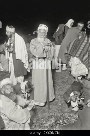 Vita in Palestina all'inizio del XX secolo. La Pasqua Samaritana sul Monte Gerizim. Il sommo sacerdote che mangia con il personale in mano. Palestina storica. Impero Ottomano. 1900-1920 Foto Stock