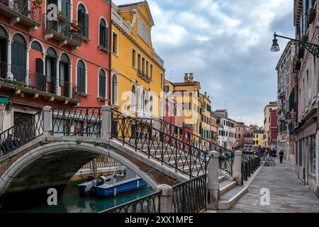 Via Venezia con case colorate e un ponte sul canale con le barche, Venezia, sito patrimonio dell'umanità dell'UNESCO, Veneto, Italia, Europa Foto Stock