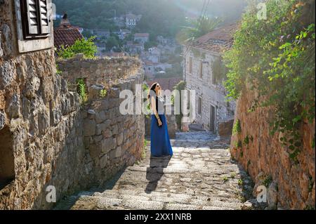 Donna che cammina su scale acciottolate, città di Lastovo, isola di Lastovo, Croazia, Europa sudorientale Foto Stock