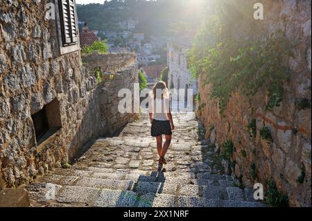 Donna che cammina lungo le scale acciottolate, città di Lastovo, isola di Lastovo, Croazia, Europa sudorientale Foto Stock