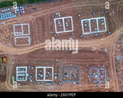 Vista aerea di un cantiere che mostra le fondamenta di nuove case costruite su un terreno Foto Stock