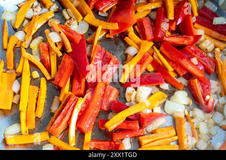 Carote, peperoni rossi, cipolle, aglio e zenzero tagliati a strisce vengono fritti in una padella. Sfondo delle loro verdure tritate. Foto di alta qualità Foto Stock