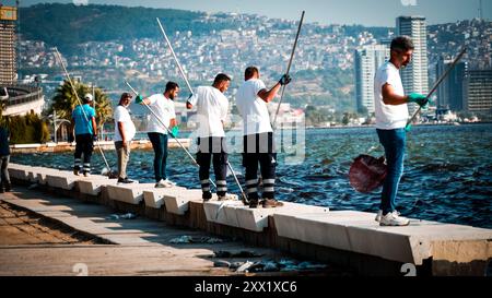 Izmir, Turchia. 21 agosto 2024. Nel Golfo di Smirne si sono verificate morti di massa di pesci a causa dei cambiamenti climatici e dell'inquinamento ambientale. I pesci morti si sono lavati sulla riva mentre gli addetti alle pulizie sono stati visti pulire la costa dai pesci morti. Crediti: İdil Toffolo/Alamy Live News Foto Stock