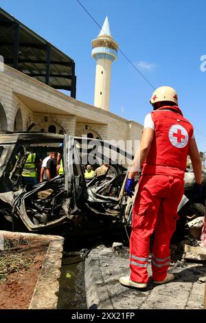 Sidon, Libano. 21 agosto 2024. Un soccorritore viene visto vicino ad un veicolo distrutto da missili di un drone israeliano a Sidone, Libano, il 21 agosto 2024. Un drone israeliano ha sparato due missili aria-superficie su un SUV civile all'ingresso meridionale della città di Sidone mercoledì mattina, uccidendo un leader delle Brigate martiri di al-Aqsa, l'ala armata del movimento di Liberazione Nazionale palestinese (Fatah), hanno detto fonti militari libanesi a Xinhua. Crediti: Ali Hashisho/Xinhua/Alamy Live News Foto Stock