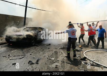 Sidon, Libano. 21 agosto 2024. La gente cerca di spegnere un incendio su un veicolo colpito da missili di un drone israeliano a Sidone, Libano, il 21 agosto 2024. Un drone israeliano ha sparato due missili aria-superficie su un SUV civile all'ingresso meridionale della città di Sidone mercoledì mattina, uccidendo un leader delle Brigate martiri di al-Aqsa, l'ala armata del movimento di Liberazione Nazionale palestinese (Fatah), hanno detto fonti militari libanesi a Xinhua. Crediti: Ali Hashisho/Xinhua/Alamy Live News Foto Stock