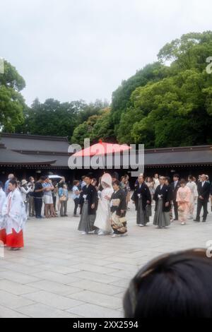 Tradizionale processione nuziale shintoista al santuario Meiji di Tokyo, Giappone, sotto un ombrello rosso. Foto Stock