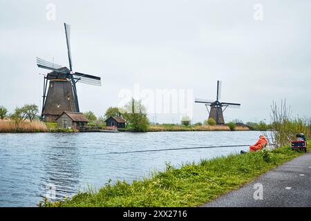 Kinderdijk, Rotterdam, Paesi Bassi - 11 aprile 2024: Storici mulini a vento e un fiume che scorre a Kinderdijk. 19 mulini a vento furono costruiti intorno al 1740 Foto Stock