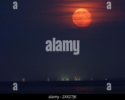 Warden Bay, Kent, Regno Unito. 21 agosto 2024. Meteo nel Regno Unito: La superluna di storione blu che si affievolisce sopra la costa del Kent vista da Warden Bay, Kent. Fig.: Il blocco torre Arlington House a Margate può essere visto in basso a sinistra. Crediti: James Bell/Alamy Live News Foto Stock