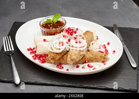 Kebab tradizionale alla griglia con melograno, cipolle e salsa piccante per un'esperienza culinaria saporita Foto Stock