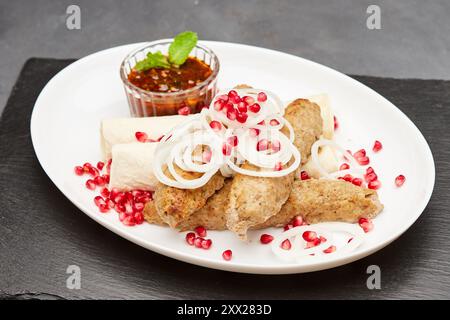 Kebab tradizionale alla griglia con melograno, cipolle e salsa piccante per un'esperienza culinaria saporita Foto Stock