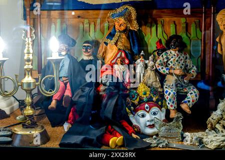 Vecchi burattini, tra cui le maschere di Arlecchino, Pulcinella e Pantalone su un tavolo illuminato con una lampada d'epoca, Firenze, Toscana, Italia Foto Stock