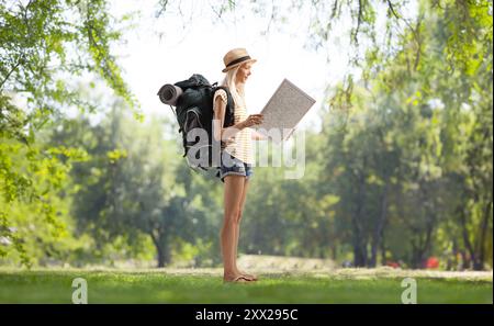 Foto a tutta lunghezza di un turista con uno zaino che legge una mappa in un parco Foto Stock