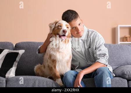 Adolescente con cane pastore australiano seduto sul divano di casa Foto Stock